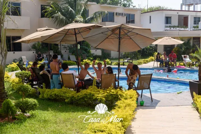 Mesas con sombrilla para convivir junto a la alberca · Hotel Casa del Mar