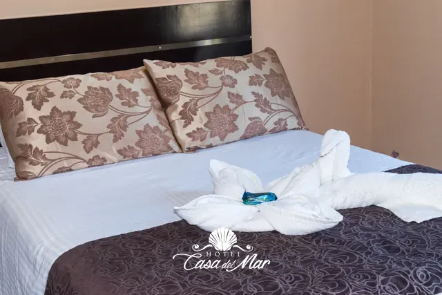 Ropa de cama blanca, cojines estampados y toallas dobladas a mano · Hotel Casa del Mar