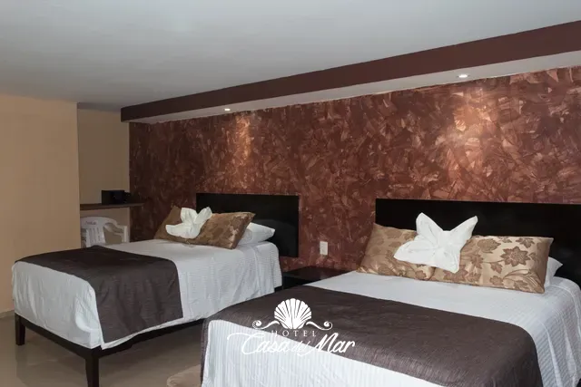 Muro de acento en tonos cobre detrás de las dos camas · Hotel Casa del Mar
